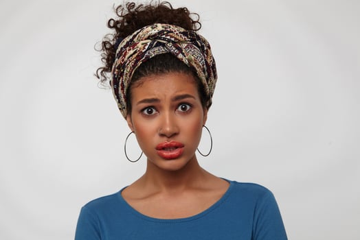 Bewildered young attractive brunette woman with casual hairstyle rounding her brown eyes while looking confusedly at camera, standing over white background photo