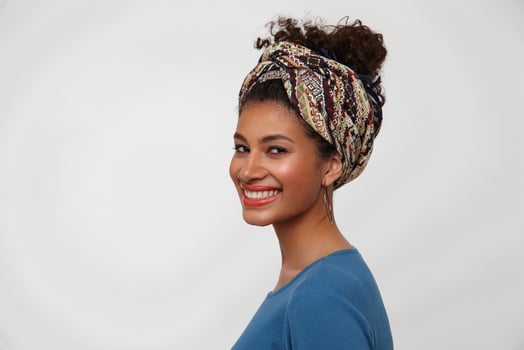 Portrait of young lovely brown-eyed curly dark skinned lady showing her white perfect teeth while smiling happily to camera, isolated over white background photo