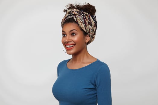 Amazed young pretty dark haired curly lady rounding surprisedly her brown eyes while looking wonderingly ahead, standing over white background in casual clothes photo