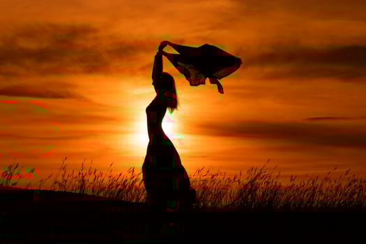 Happy woman dancing and holding scarf while enjoys spending time at sunset. photo