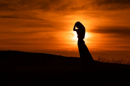 Silhouette of a sad woman standing at the sunset. photo