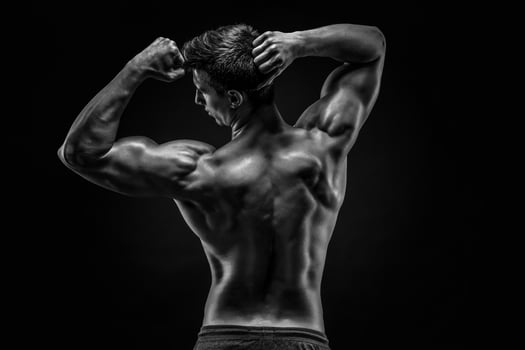 Healthy muscular young man showing back and biceps muscles photo