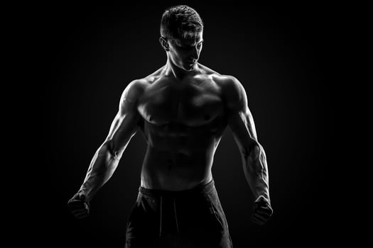 Sexy muscular man posing with naked torso on black background photo