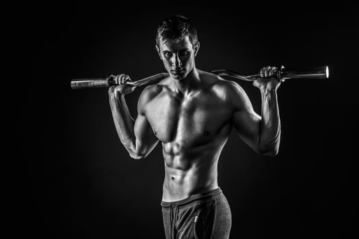 Strong man holding barbell on his shoulders, looking at camera photo