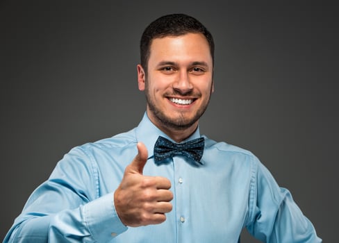 Smiling young man making the ok thumbs up hand sign photo