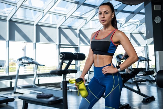Girl standing with water bottle at gym after training photo
