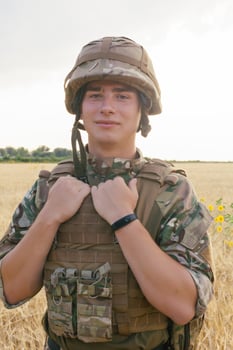 Soldier man standing against a field photo