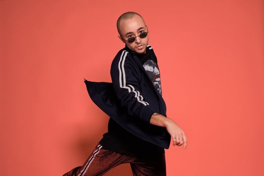 Studio shot of a young tattoed bald man posing against a pink background. 90s style. photo