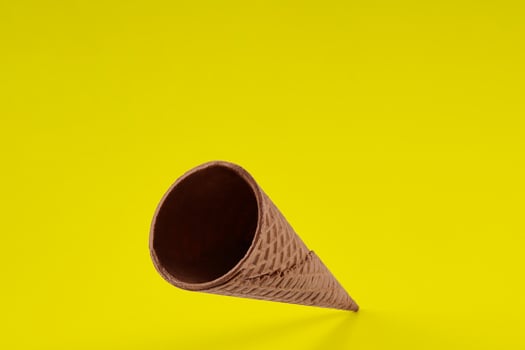 Empty, yummy wafer cone for ice cream against yellow background. Concept of food, treats. Mockup, template for your advertising and design. Close up photo