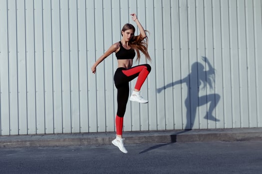 Full length of healthy female exercising and jumping outdoors. photo