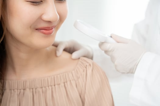 skin problem and beauty. asian woman use magnifying glass look itchy skin from skin allergic, shocked, steroid allergy, sensitive, chemical allergy, rash, insect bites, Seborrheic Dermatitis. photo