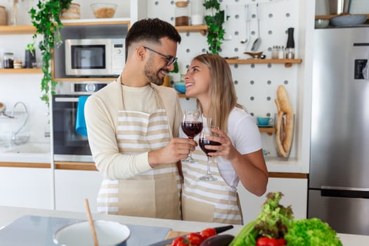 Romantic young couple cooking together in the kitchen,having a great time together. Man and woman laughing and drinking wine photo