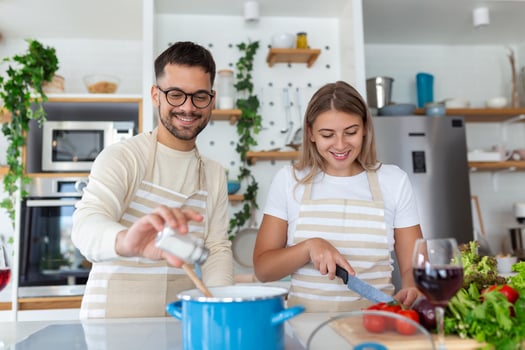Smiling young couple cooking food in the kitchen together in the kitchen,having a great time together. Man and woman laughing and drinking milk in the morning with breakfast photo