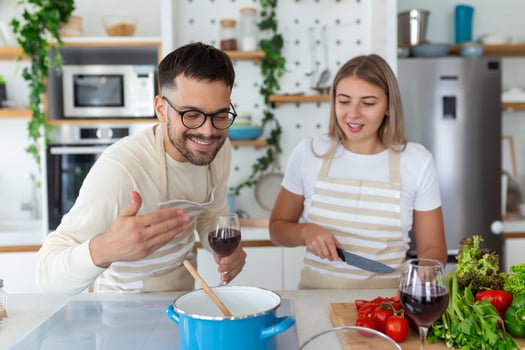 Romantic young couple cooking together in the kitchen,having a great time together. Man and woman laughing in the morning with breakfast photo