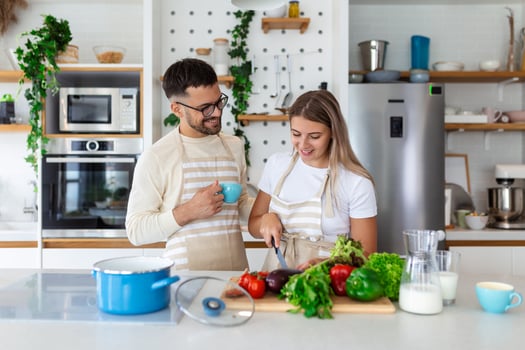 Portrait of happy young couple cooking together in the kitchen at home. romantic Attractive young woman and handsome man are enjoying spending time together while standing on light modern kitchen. photo