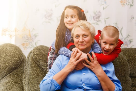 Grandmother and grandchildren sitting together on sofa in living room photo