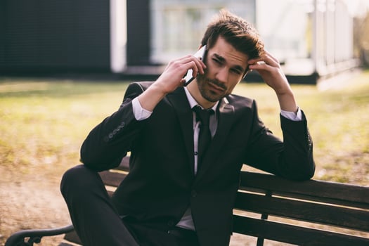 Worried businessman using phone while sitting outdoor.Toned image. photo