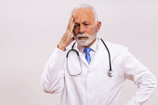 Image of tired senior doctor having headache on gray background. photo