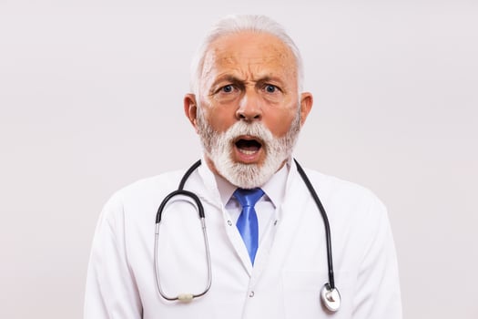 Image of shocked senior doctor on gray background. photo