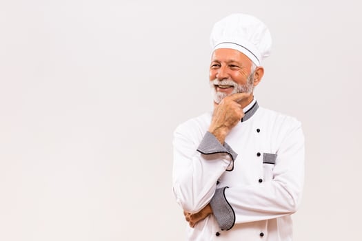 Portrait of senior chef thinking  on gray background. photo