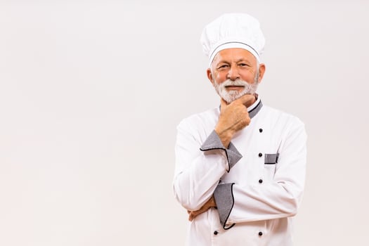 Portrait of senior chef thinking  on gray background. photo