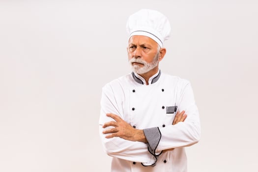 Portrait of angry senior chef  on gray background. photo
