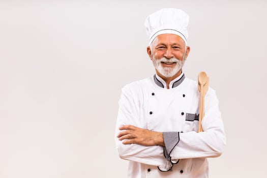 Portrait of  senior chef with work tool on gray background. photo