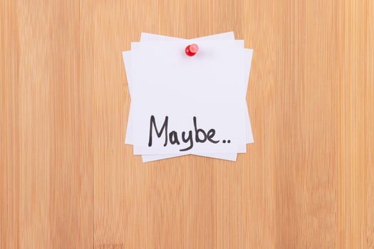MAYBE.. White Sticky Notes with Written Word MAYBE, Pinned to the Wooden Message Board. To Do List Reminder in the Office. Memo Note at Work photo