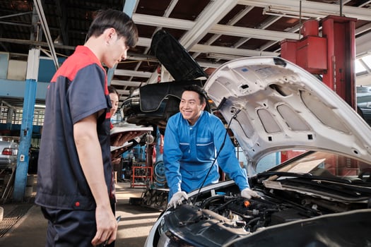 Asian male professional automotive engineer supervisor describes car engine maintenance and repair work with mechanic worker staffs team in fix service garage, specialist occupations in auto industry. photo