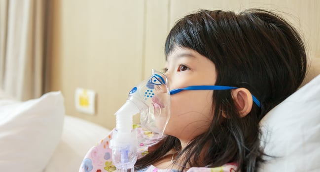 Sick little asian girl inhalation with nebulizer for respiratory treatment photo