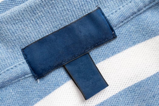 Blank blue laundry care clothes label on shirt fabric texture background photo