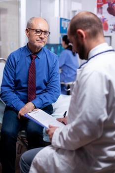 Old man answering doctor questionnaire during examination in hospital room. Converstation with medical stuff clinic medicine healthcare, senior, coat, clipboard. photo