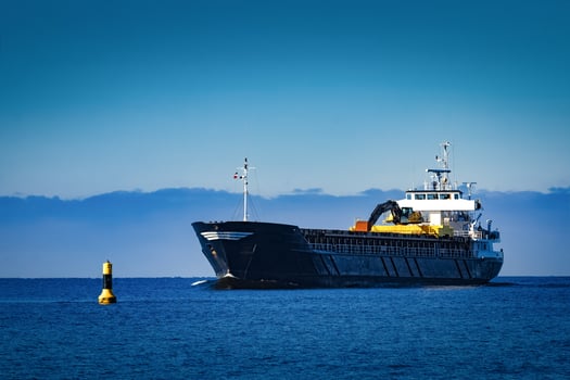 Black Sailing Bulk Carrier. Cargo Ship with Long Reach Excavator Moving in Still Water at Sunny Day by the Sea photo