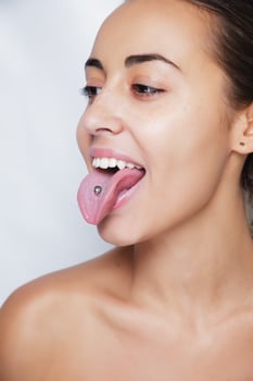 Beautiful woman sticking out her tongue and showing young piercing photo