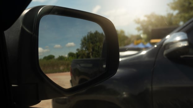 Mirror wing of car with other car parking beside. In ther mirror wing with soil road in the glass. photo