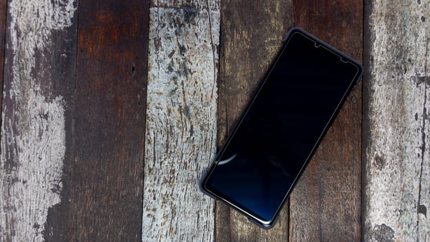 Above view of smart phone with a shiny black frame. Placed on a wooden floor that is a variety of beautiful. photo