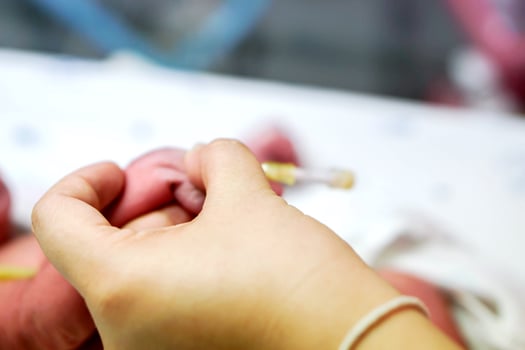 Nurse hands press on IV Catheter and sick newborn baby's hands to prepare using medical adhesive plaster stick and wrap safely to fill the saline solution and medicine. photo