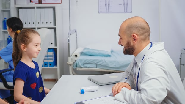 Friendly doctor doing high five with child sitting at the desk. Healthcare physician specialist in medicine providing health care services radiographic treatment examination in hospital cabinet photo