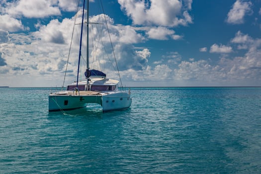 Luxury yacht in open waters with beautiful clouds. Catamaran white sailboat in tropical ocean lagoon, sea horizon under sunny skyline. Idyllic outdoor sport and travel recreation landscape, seascape photo