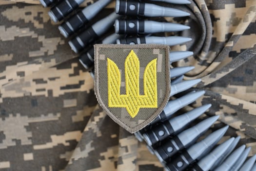 Ukrainian army symbol on machine gun belt lies on ukrainian pixeled military camouflage photo