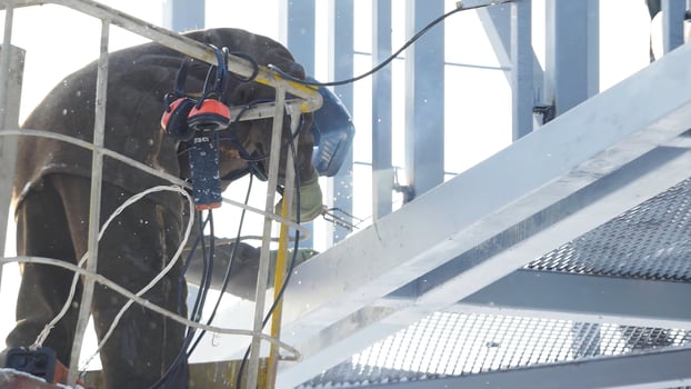 Construction workers working on scaffolding, Man Working on the Working at height with blue sky at construction site. Worker using electric wheel grinding on steel structure in factory. Work on high photo
