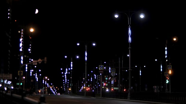 Empty residential street in the late evening with road signs and lanterns on black sky background. Stock footage. Night urban street lit by neon lights. photo
