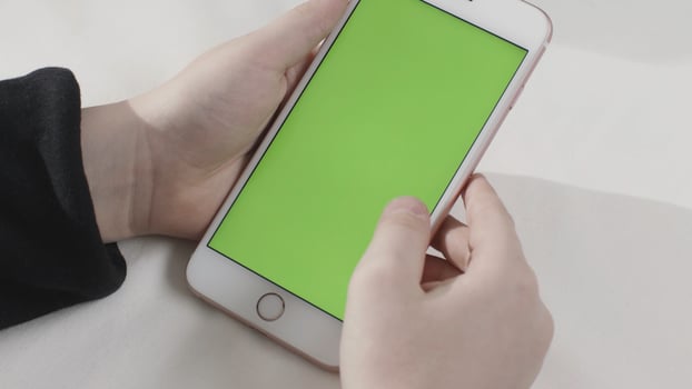 Hand holding touch green screen smart phone on white background. Stock footage. Hand tapping on a cell phone with chroma key. photo