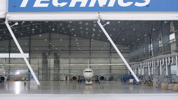 Roller shutter door and concrete floor of airport hangar and airplane background. Airport hangar from the outside with big tall doors. Front view. Aircraft Hangar photo