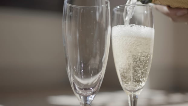Close-up of pouring champagne into elegant wine glasses. Action. Transparent champagne glasses for date. Pouring champagne by glass on sunny day photo