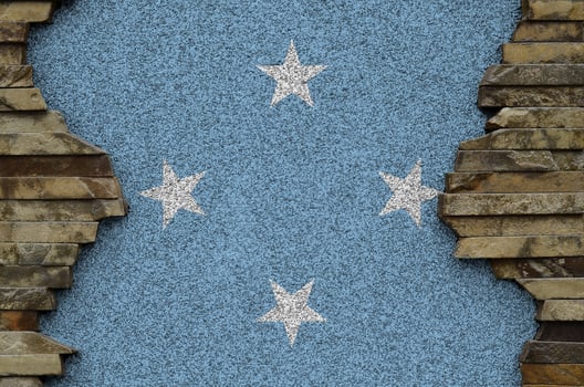 Micronesia flag depicted in paint colors on old stone wall closeup. Textured banner on rock wall background photo
