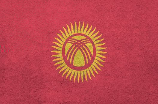 Kyrgyzstan flag depicted in bright paint colors on old relief plastering wall. Textured banner on rough background photo