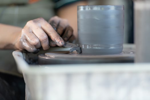 hands of a potter, creating an earthen jar on the pottery wheel photo