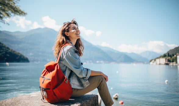 AI generated a woman sitting on the shore of lake como holding her backpack while smiling photo
