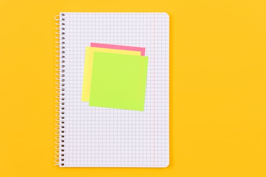 A Notepad with Sticky Notes Lying on Yellow Table Blank Template. Top View, Flat Lay photo